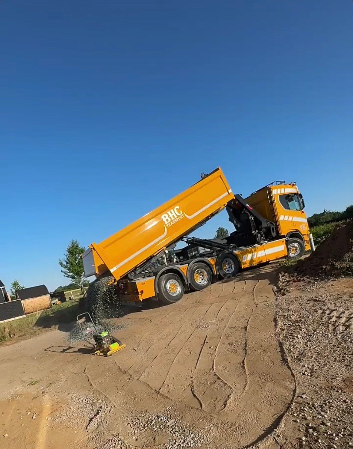 Lastbil tipper grus ud til indkørsel